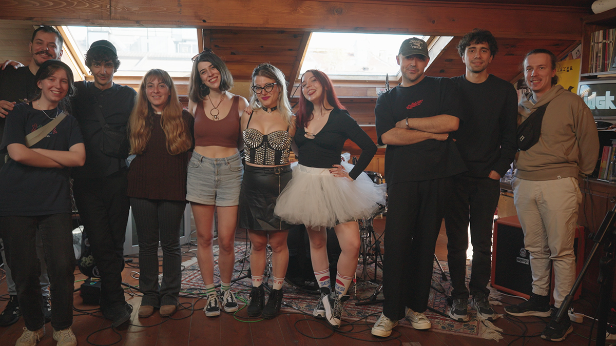 The IDGK crew, a group of ten people standing close to each other in a performance space